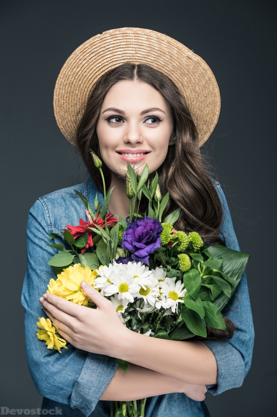 Devostock beautiful cheerful girl in straw hat holding flowers for interna