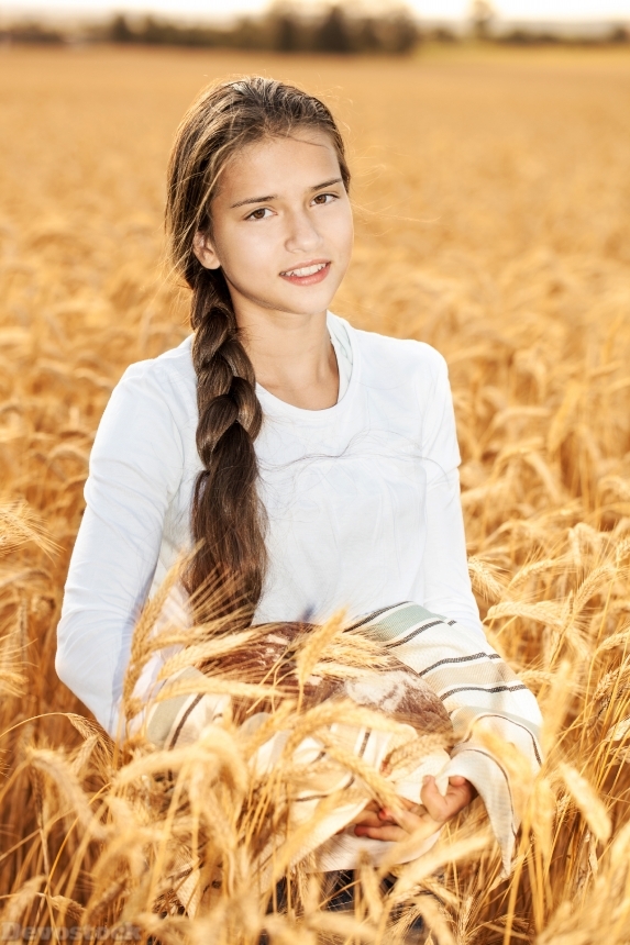 Devostock Happy girl on field of wheat with bread