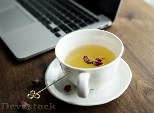 Devostock A cup of nice herbal tea next to a computer laptop