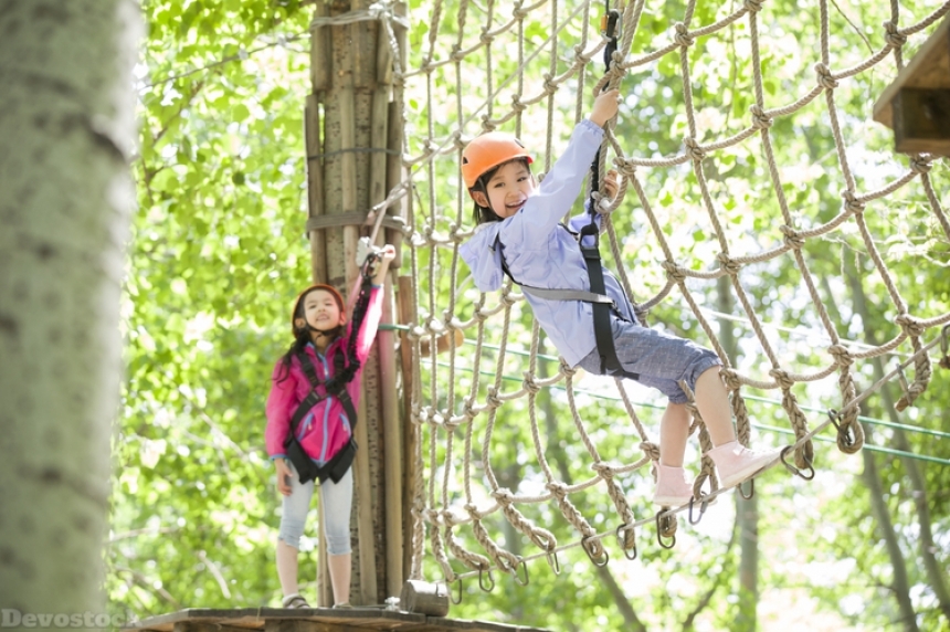 Devostock Little girls playing in tree top adventure park
