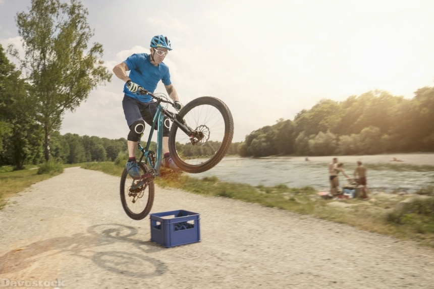Devostock man jumping with mountainbike over beer box near river,sunset,acrobatic