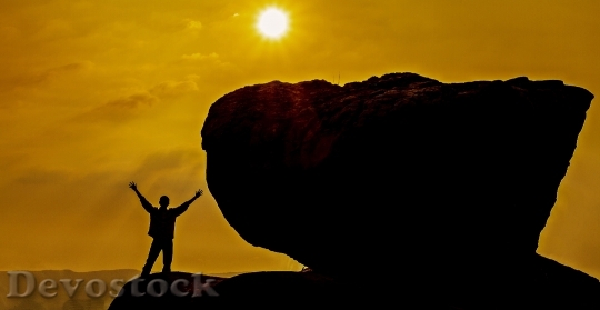 Devostock A man standing near huge rock during golden hour