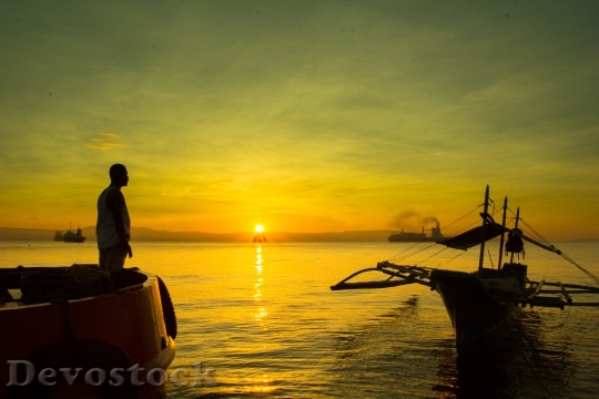 Devostock A man standing on boat during sunrise, davao, philippines