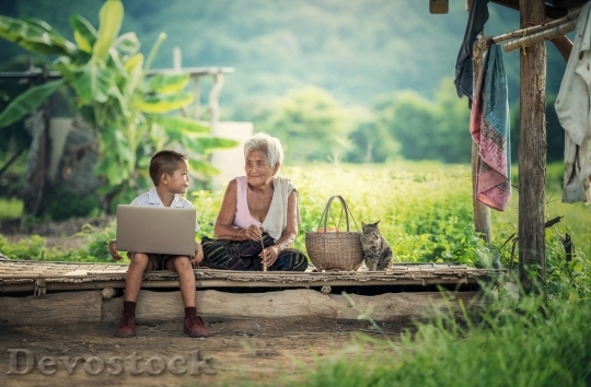Devostock Boy plaign with his laptop in the wood with old woman