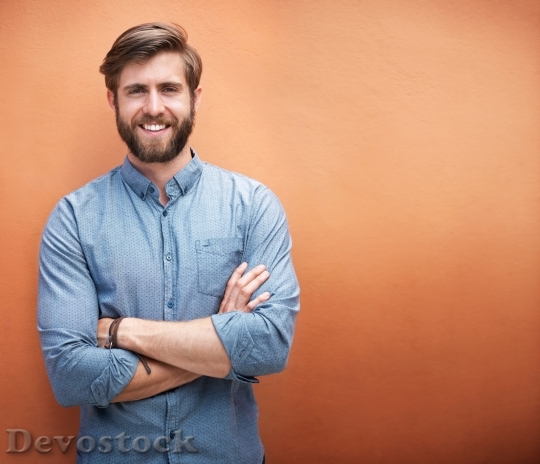 Devostock Cropped portrait of a trendy young man standing against an orange 