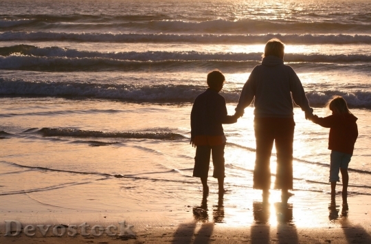 Devostock Family at the beach holding hands