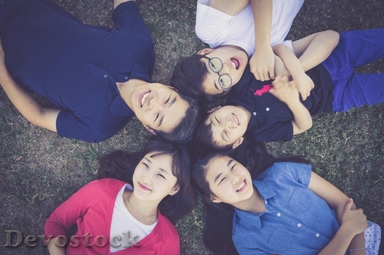 Devostock Happy asian family lying on the grass in circle