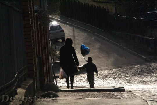 Devostock Mother and son walking down the street in the shadow