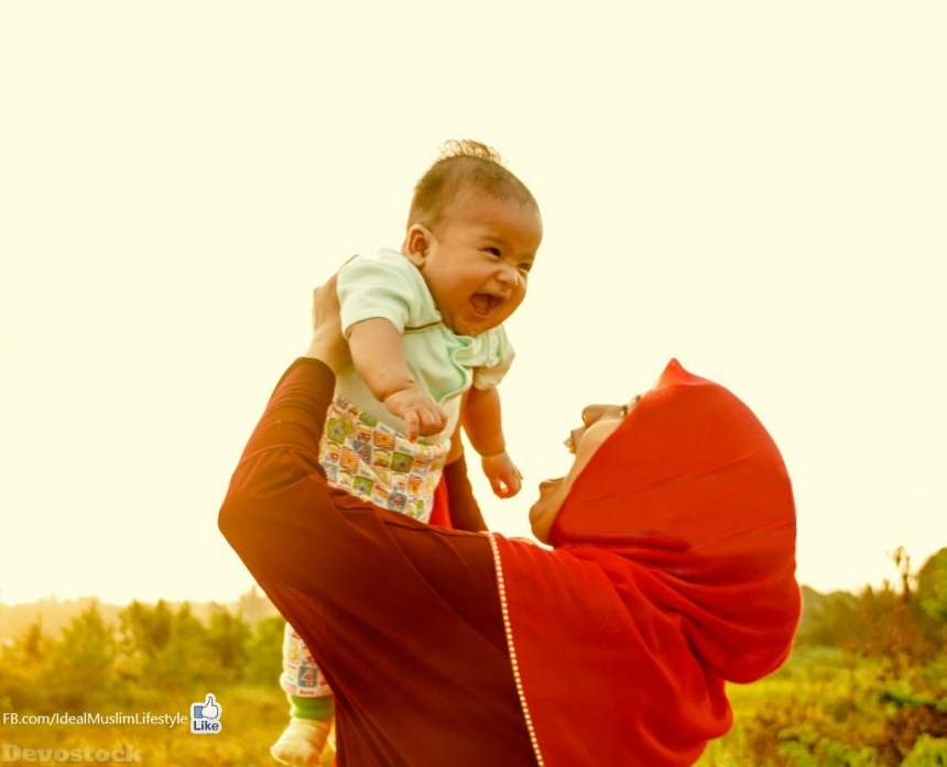 Devostock Muslim mother carrying her smiling baby 