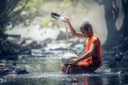 Devostock Selective focus photography of monk in river dripping water on stainless steel container